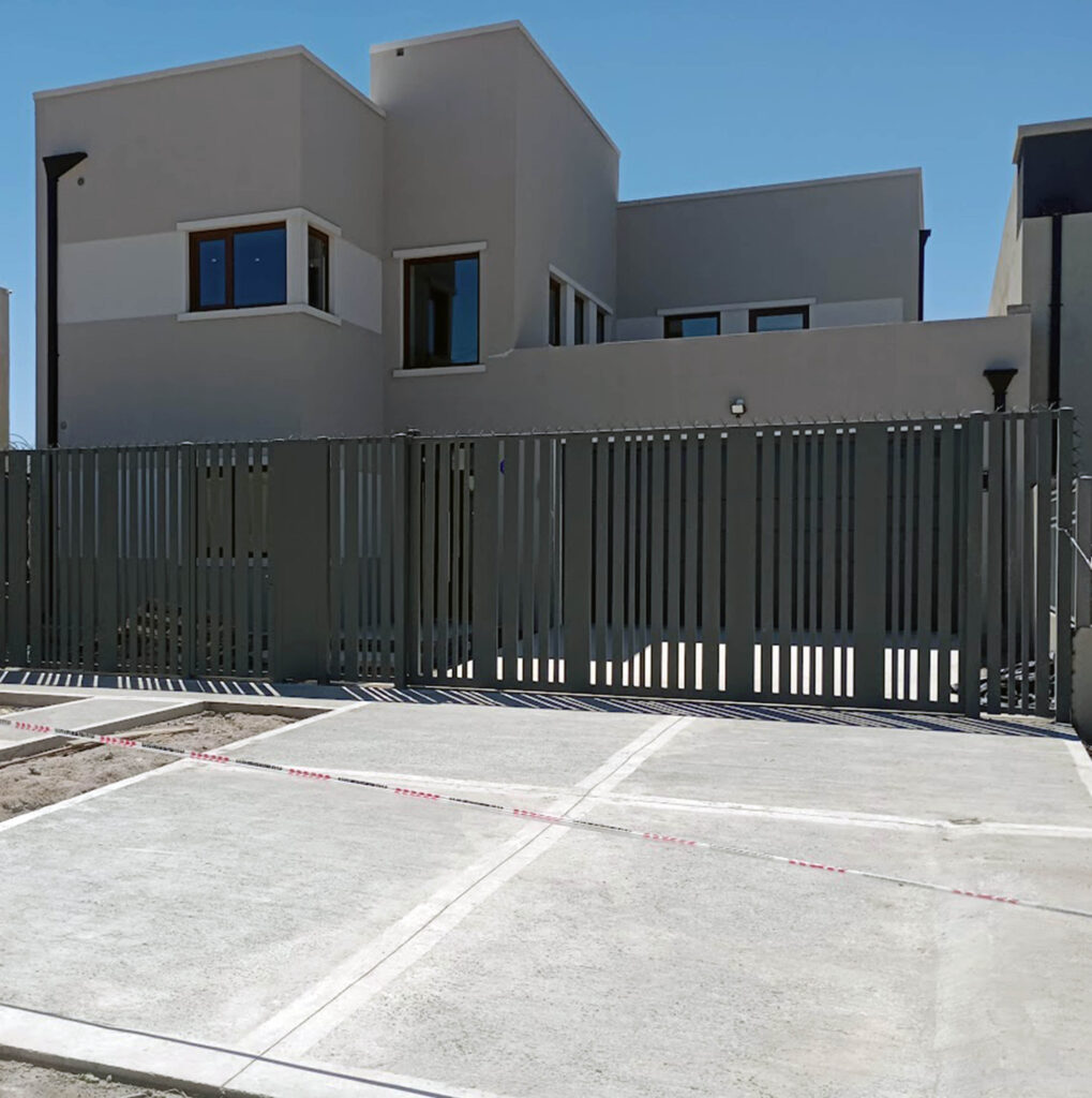 Vivienda moderna de líneas rectas con fachada minimalista, volúmenes cúbicos y cerco metálico frontal.