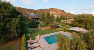 Vista aérea de residencia privada con piscina y jardín al atardecer – Proyecto residencial Cipolletti, Río Negro. Integración con mesetas rocosas y vegetación nativa